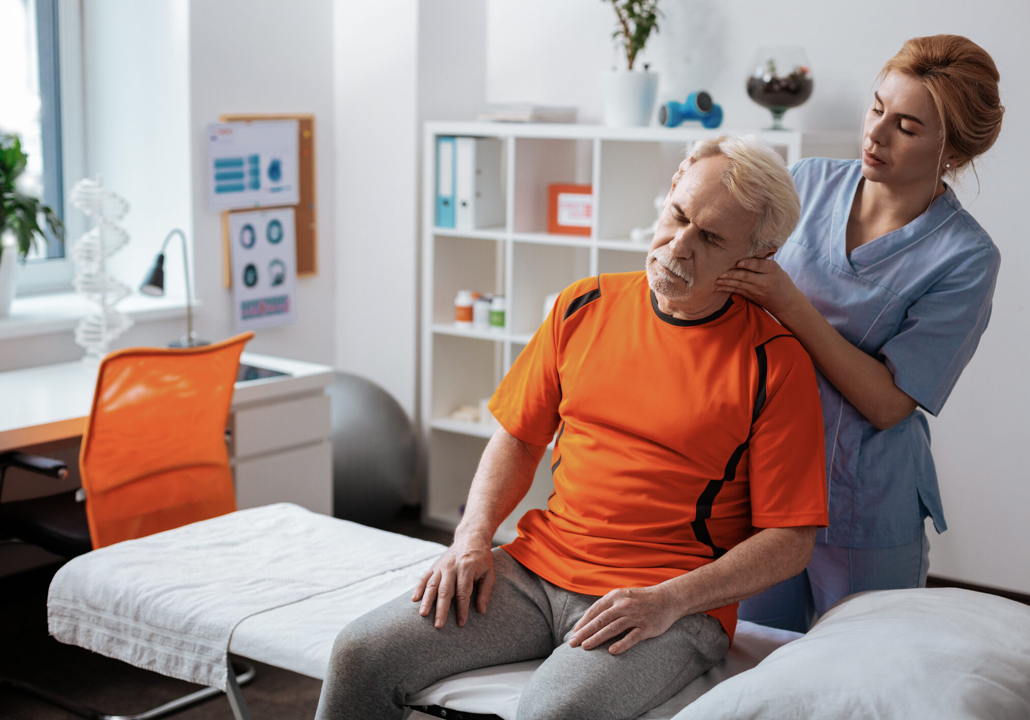 Relaxing muscles. Nice senior man sitting in front of the nurse while receiving a professional head massage